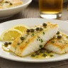 Cod Piccata served on an elegant dinner table with lemon slices