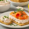 Close-up of creamy salmon cream cheese spread on crackers with smoked salmon and fresh herbs